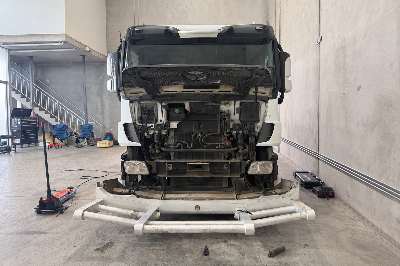 Mechanic servicing a heavy vehicle diesel engine in a clean workshop